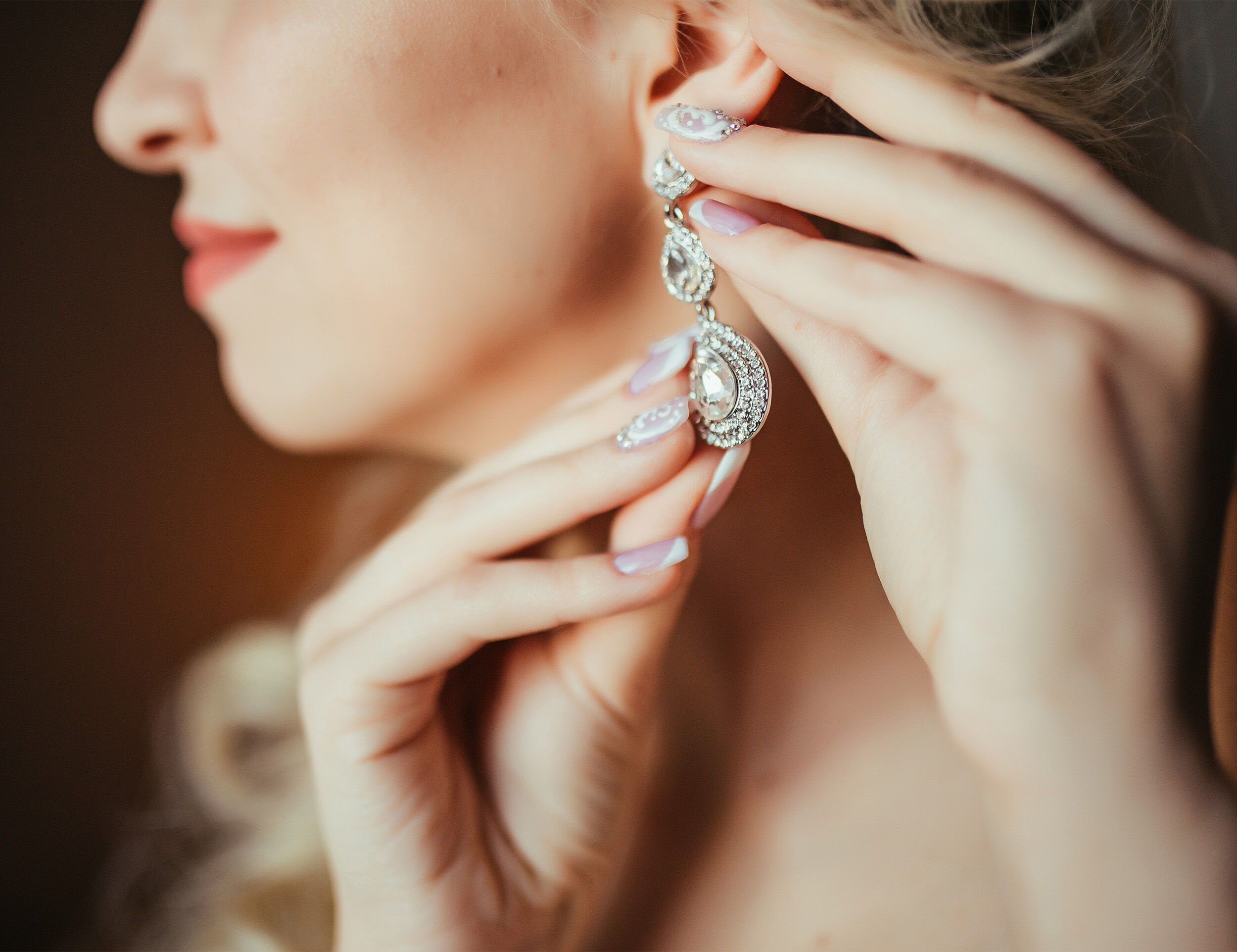 A woman showcasing elegant diamond earrings for a bridal look.